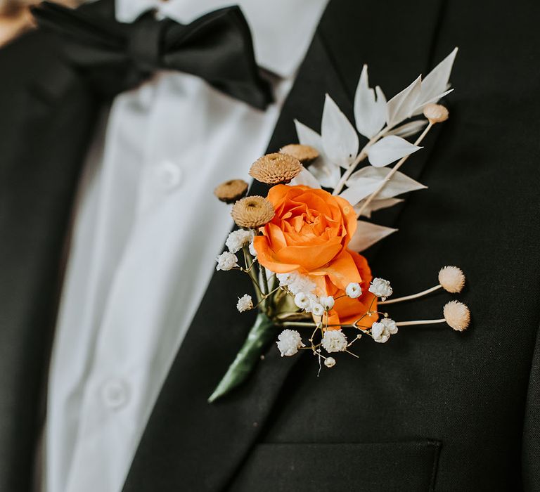 orange flower buttonhole with foliage 