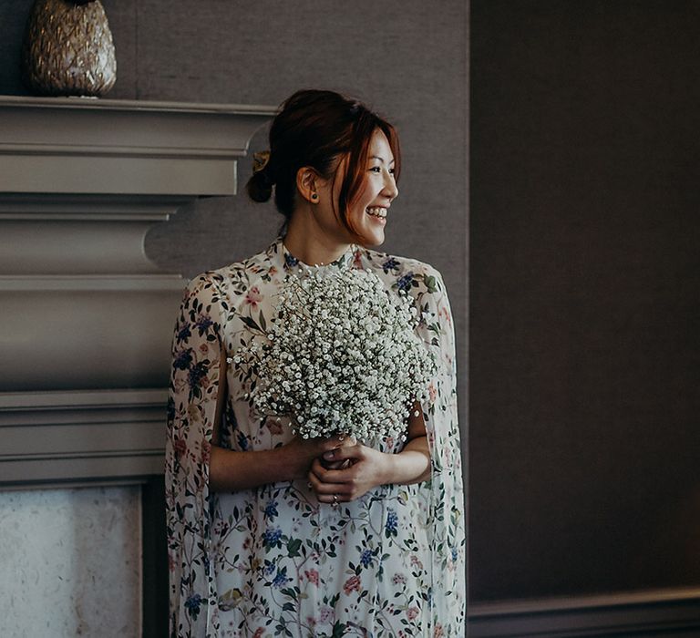 Beautiful East Asian bride in a short wedding dress with blue floral design and cape sleeves holding a gypsophila wedding bouquet 