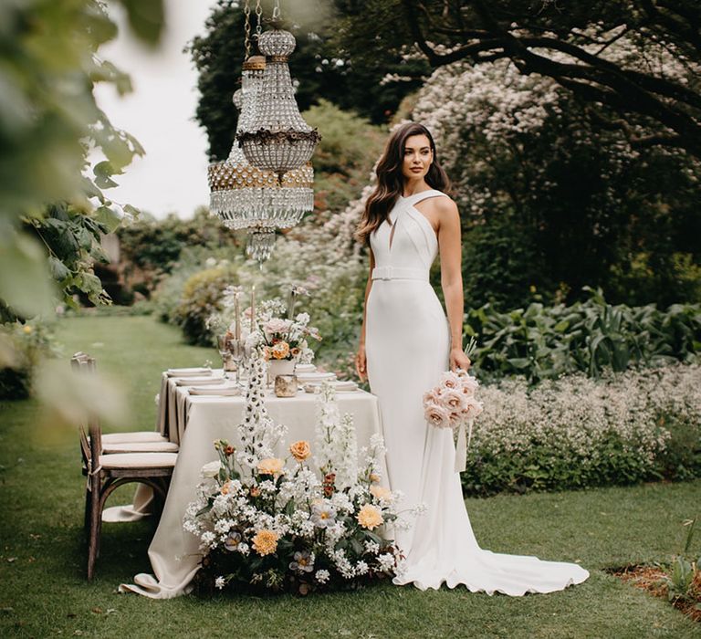 Enchanting garden wedding reception with white and peach flowers and hanging chandelier installation