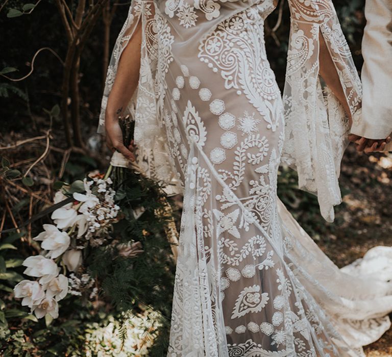 Boho bride in a lace Rue De Seine wedding dress holding hands with her groom in beige suit 