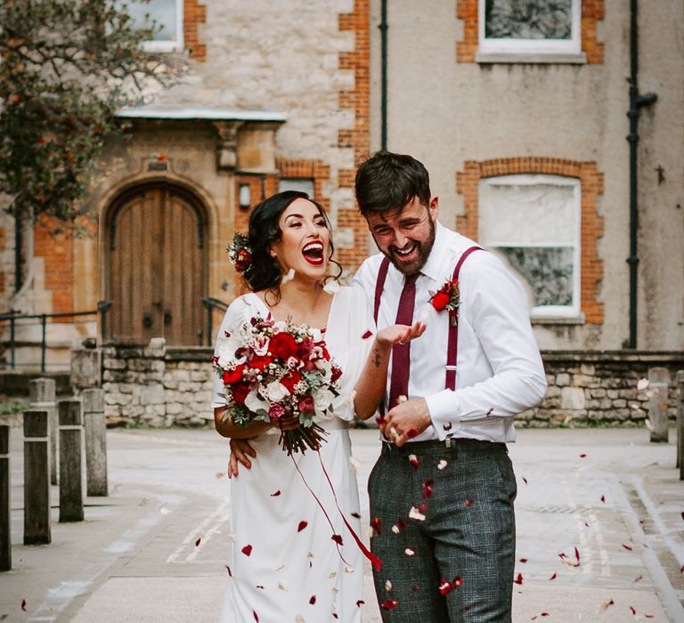 Beautiful bride wearing a bright red lipstick to match her wedding bouquet flowers and her grooms braces 