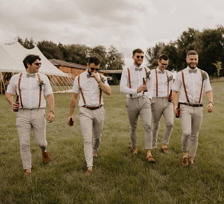 Groom and his groomsmen walk across field on his wedding day at Duddon Mill Farm | Mark Bamforth Photography