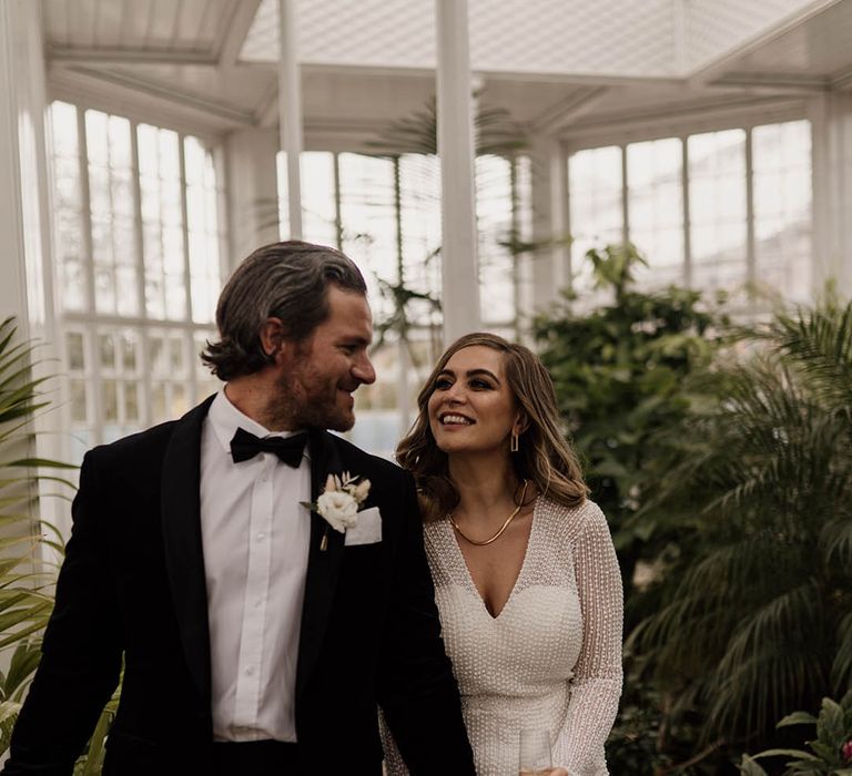 Groom in a tuxedo holding hands with his bride in a beaded wedding dress at Tatton Park wedding 