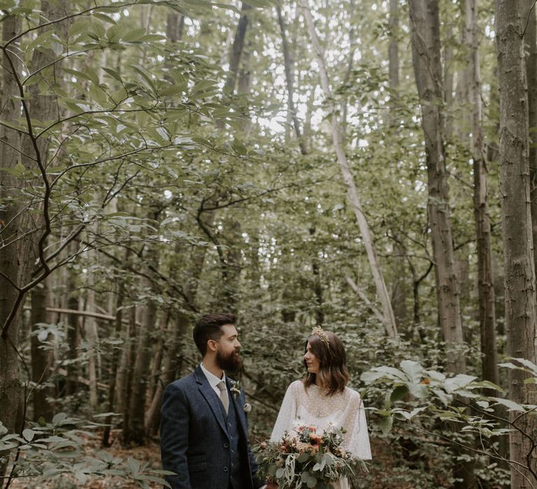 Bride & groom look lovingly at one another as bride wears E&W Couture wedding gown