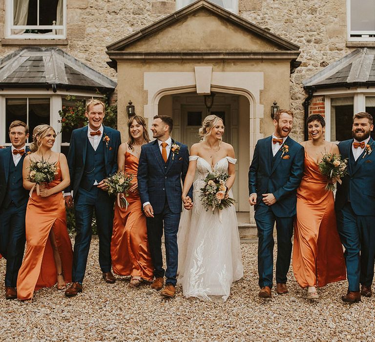 Bridesmaids in orange dresses with groomsmen in blue suits