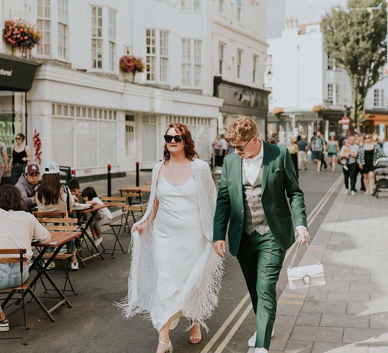 Bride & groom walk hand in hand on their wedding day through the streets of Brighton