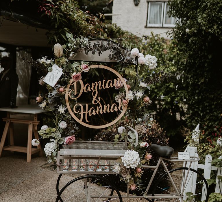 Three wheeled wedding bike complete with personalised name sign and tray filled with glasses 