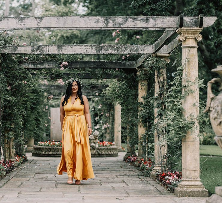 Bridesmaid walks down the aisle wearing sunflower yellow bridesmaid dress