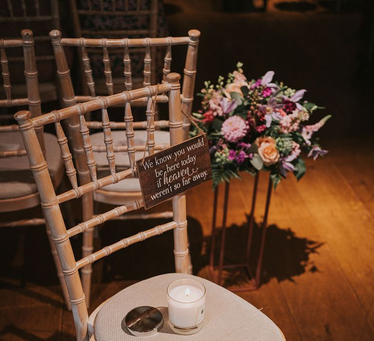 Light wooden and cream chair with a lit candle and wooden plaque for those lost