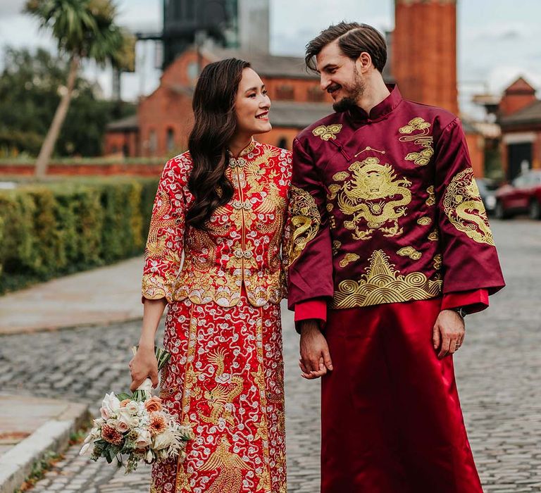 Bride and groom in traditional red and gold Chinese wedding attire with bride wearing matching shoes