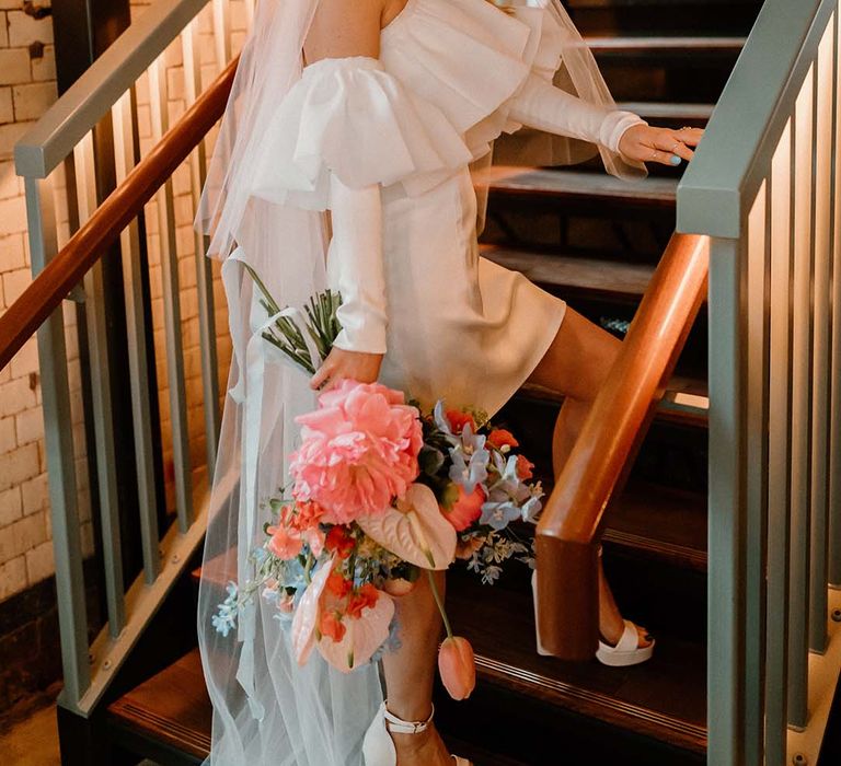 Stylish bride in an off the shoulder short wedding dress with detachable long sleeves and long wedding veil 