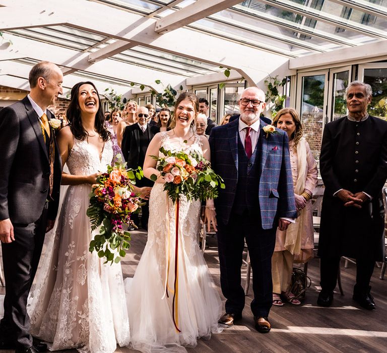 Brides stand with their fathers at Foxtail Barns wedding venue for their ceremony