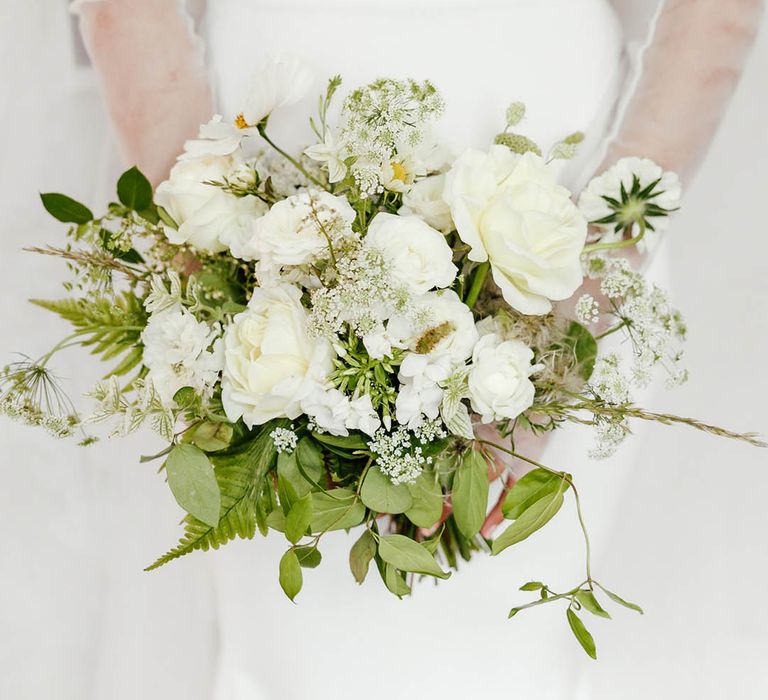 White flower wedding bouquet with green foliage for bride in boned off the shoulder wedding dress