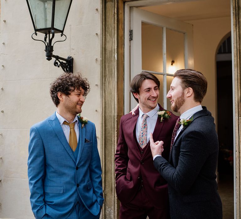 Groom speaks and catches up with guests in different colour suits after wedding ceremony 