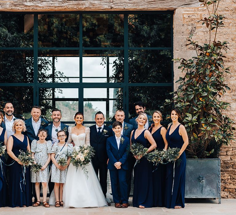 Bride & groom and their wedding party in blue smile for the camera 