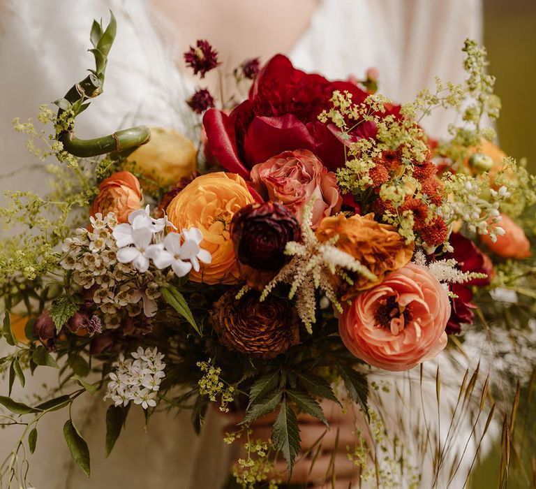 Red, orange and yellow wedding bouquet with ranunculus and bamboo stems 