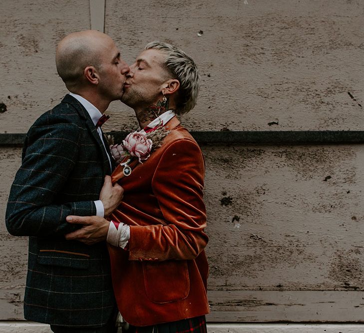 Grooms kiss outdoors on their wedding day 