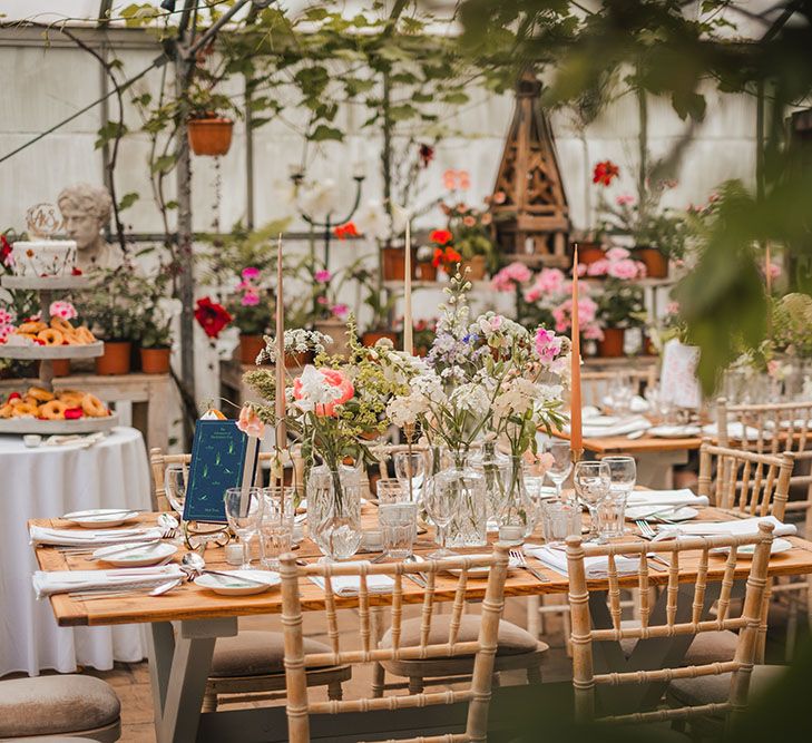 Wooden tables complete with colourful florals, pastel candles, and book in the West Green House Gardens