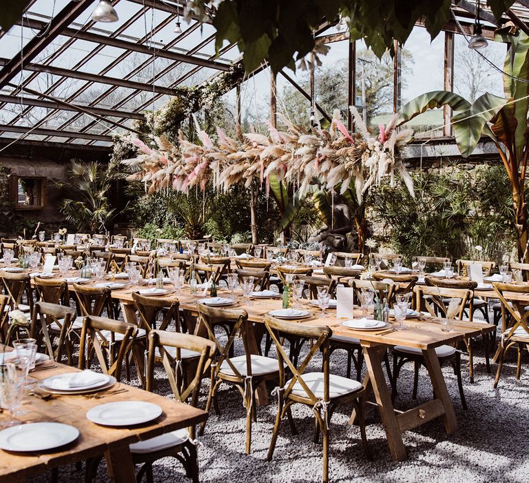 Wedding table settings with pink and green glassware with beige and pink pampas grass flower installation at the glasshouse wedding venue 