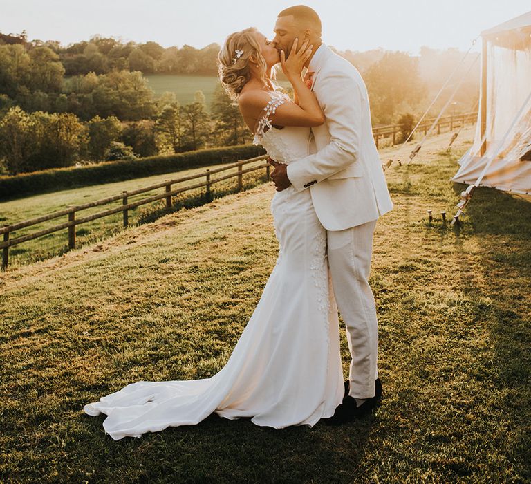 Bride and groom kiss for their golden hour couple portrait 