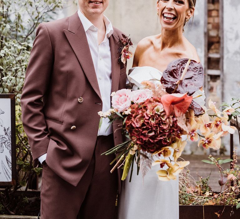 Bride and groom smile brightly at their city wedding with a pink and brown colour palette 