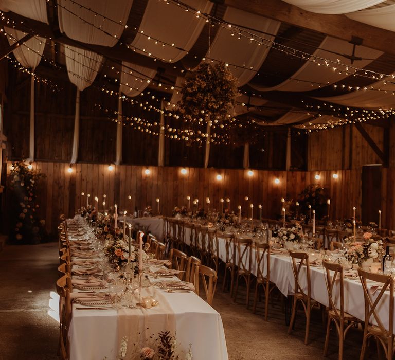 White wedding drapes and fairy lights hangs on the ceiling with pink and muted tone tablescape and soft romantic lighting 