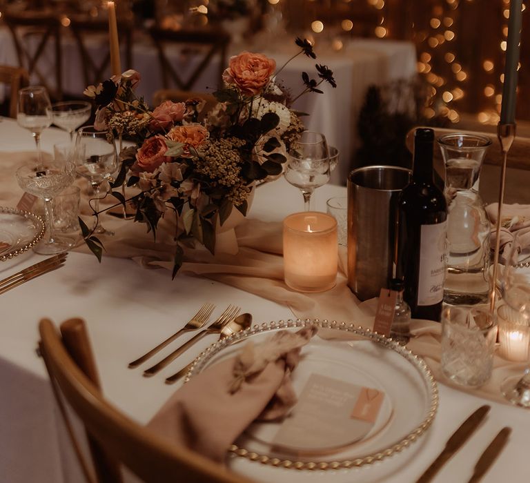 Gold cutlery, gold edge charger plates, grey and pink wedding stationery, blush table runner and napkins with candle light and fairy lights