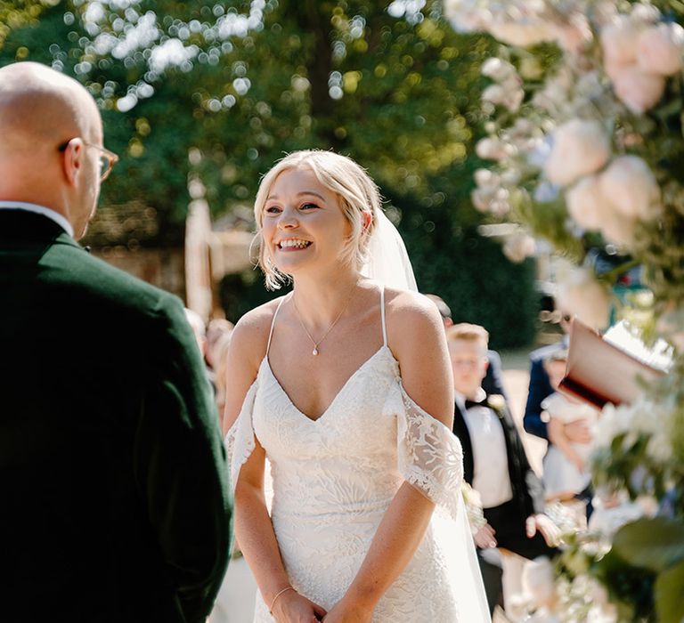 Bride wears off the shoulder lace wedding dress during summer outdoor wedding ceremony