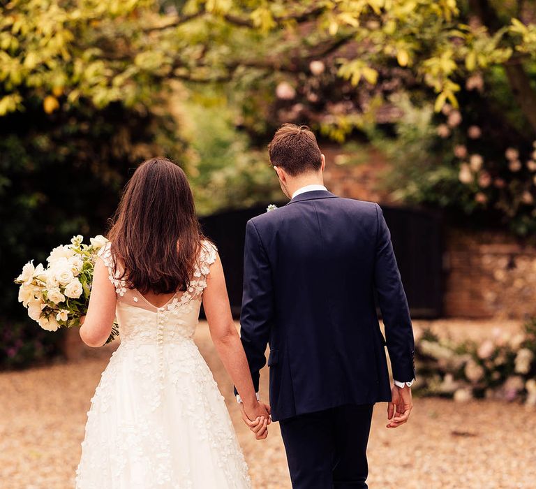 Bride and groom walk holding hands with the bride in a bespoke Phillipa Lepley wedding dress 