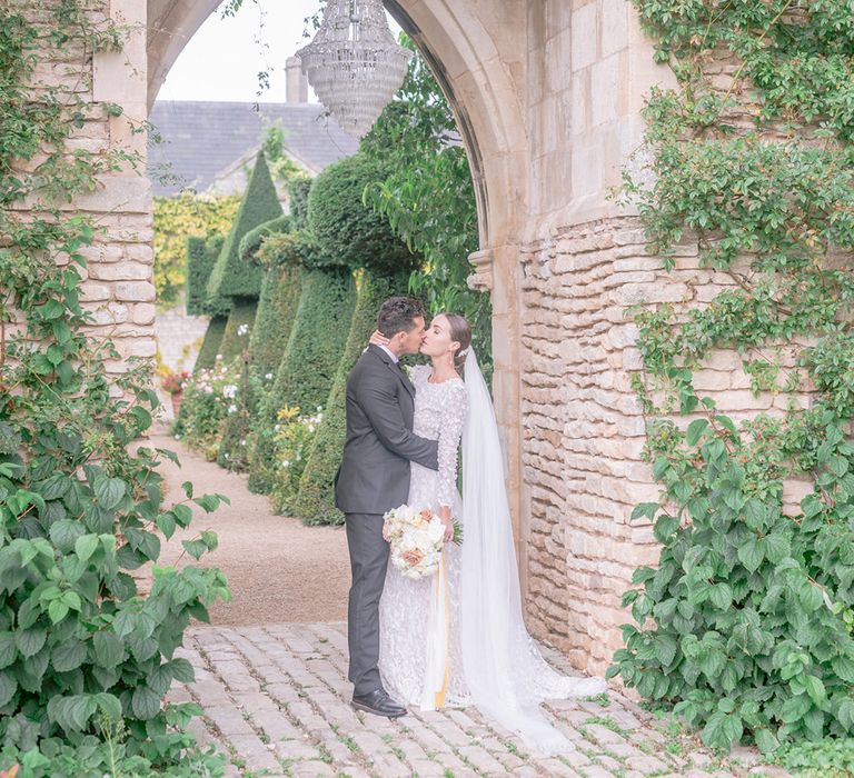 The bride and groom share a kiss underneath the crystal chandelier 