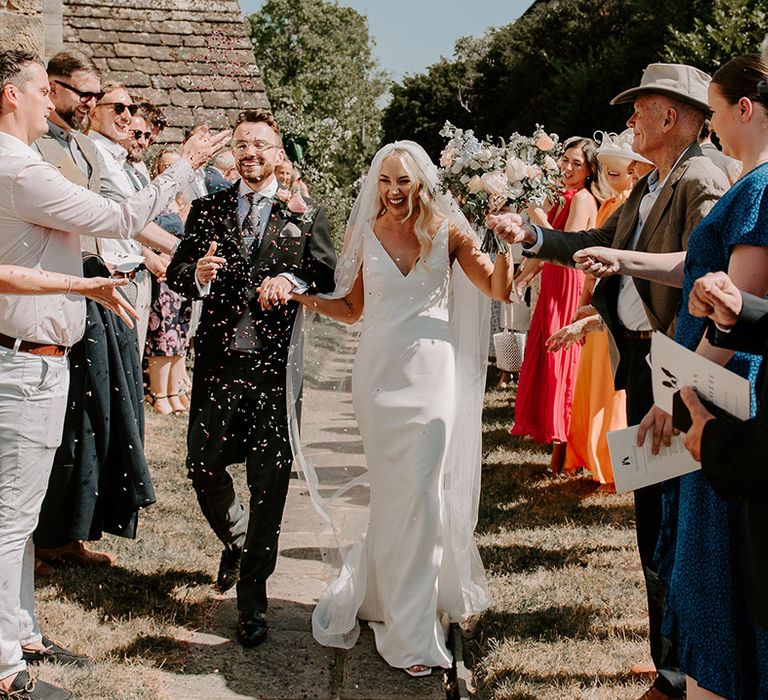 The bride and groom have a confetti exit after their traditional church wedding ceremony 