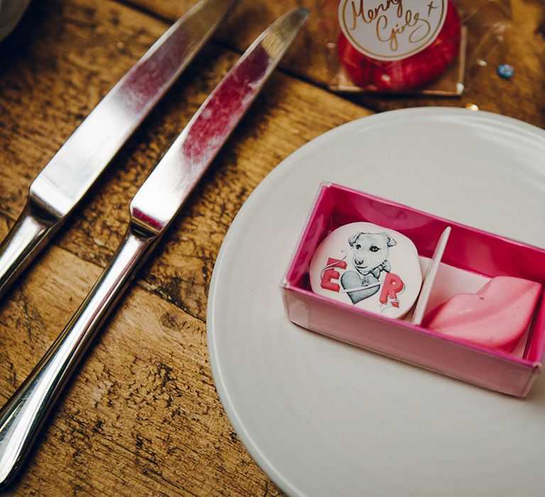 Small pink box with personalised wedding favours inside; one biscuit with Dolly the dog and couple's initials, the other a rosy pink lips biscuit