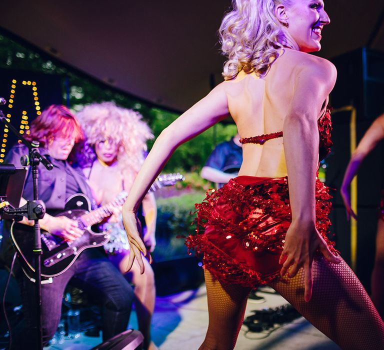 Two wedding performers wearing red open back detail sequin fringed party dresses and fishnet tights dancing on stage 