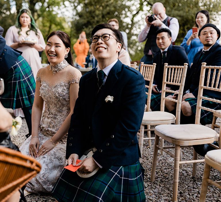 Bride wears bespoke reception dress as she sits beside her groom in a green tartan kilt