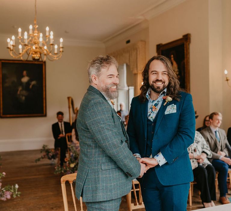 Groom wears blue three piece suit with floral shirt and matching pocket square during wedding ceremony 