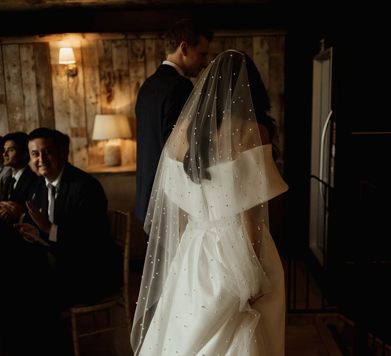 Off the shoulder Eve Lendel wedding dress worn by the bride with a pearl wedding veil for rustic luxe wedding at Hidden River Barns