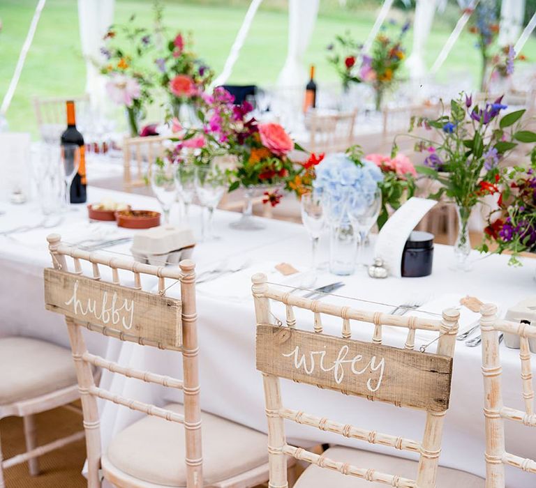 Wooden wedding signs for the bride and groom on the white wedding chairs for the reception at the top table 