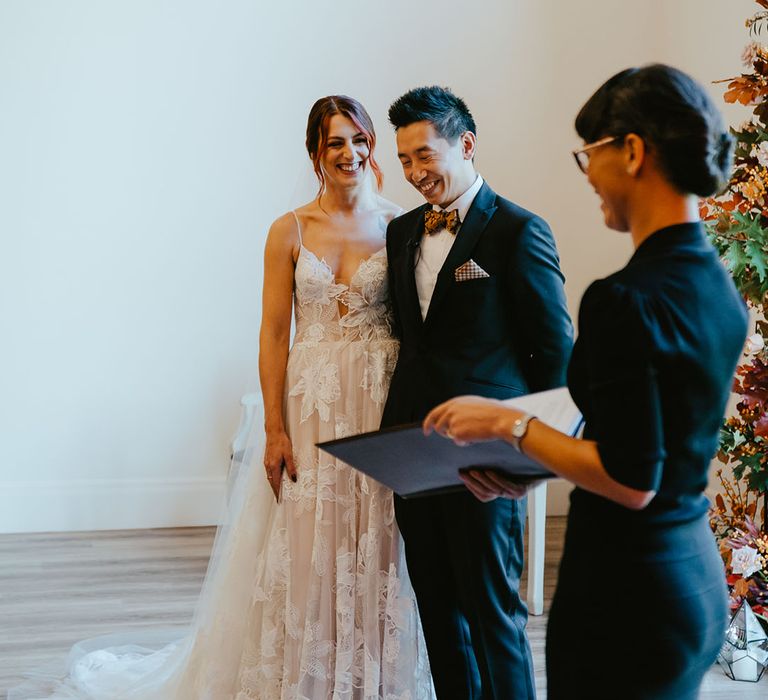 Bride in Madi Lane Bridal wedding dress stands beside her groom in black-tie during personal wedding ceremony 