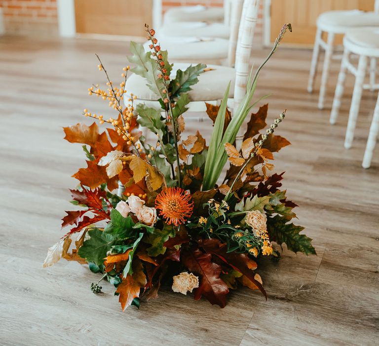  Burnt orange wedding flowers line the aisle of Reymerston Hall wedding venue  