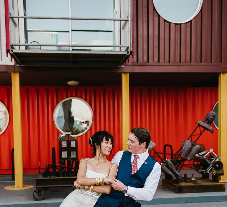 Groom dances with his bride in silver wedding dress with ruffled skirt to the bottom 