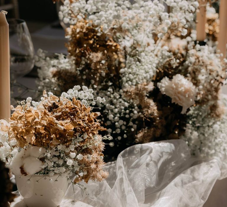 Luxurious and minimalistic wedding decor - neutral toned baby's-breath and dried flowers in ceramic vases, tea light candles in ceramic candle holders and sheer tulle fabric 