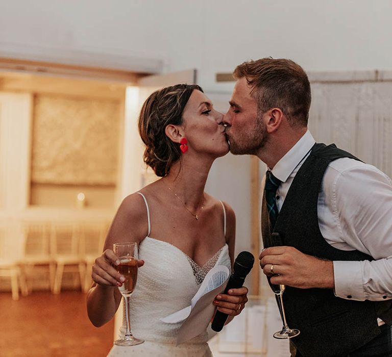 Bride and groom kiss and toast during their joint wedding speech 