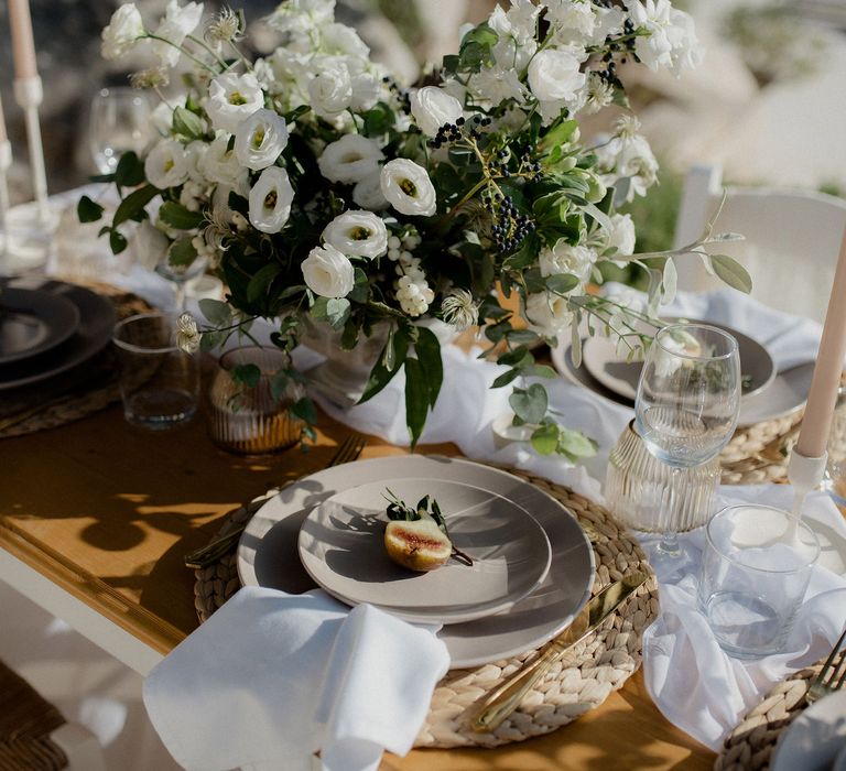 Wedding tablescape with white roses, white berries, italian ranunculous and eucalyptus, figs, ribbed jars and blush tapered candles