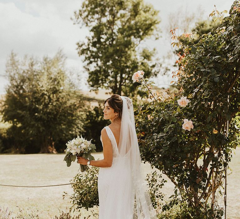 Bride in low back Made With Love Bridal wedding dress with cathedral length wedding veil posing for bridal portrait 