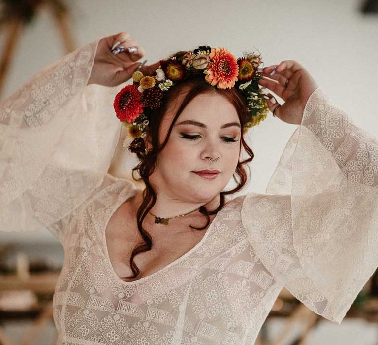 Bride wearing sheer overlay long bell sleeve wedding dress and boho rustic dried flower crown at The Barn at Avington