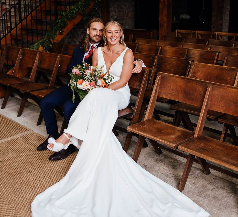 The Barn at Botley Hill in Surrey wedding with the bride and groom taking a seat together at the ceremony barn 