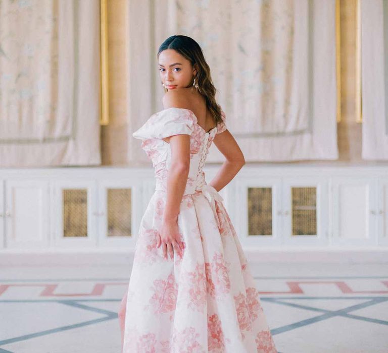 Bride in off the shoulder white and pink floral patterned bridal gown with black bow and front slit at Settrington Orangery wedding venue