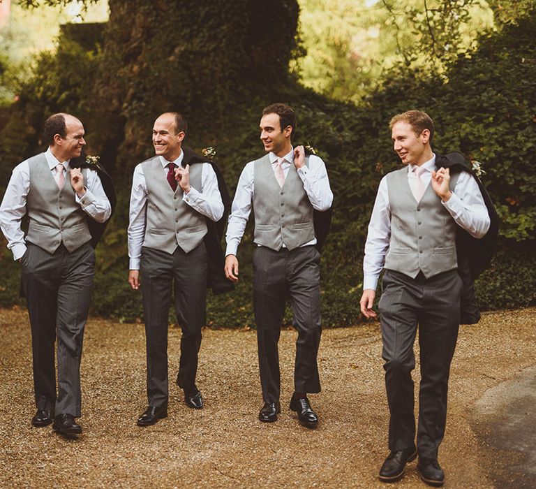 Groom and groomsmen posing together holding their suit jackets for posed photo 