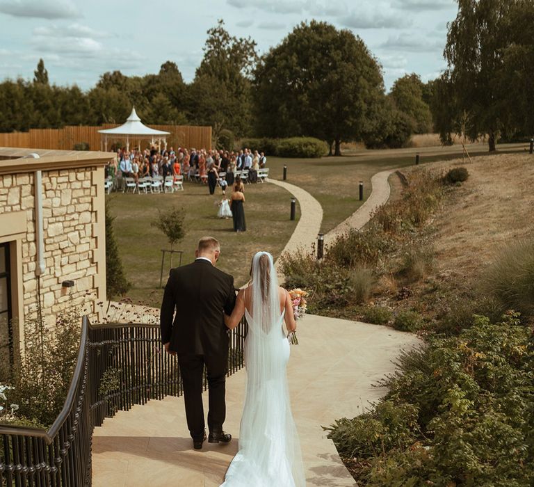 Bride and father of the bride walk hand in hand for the walk to the aisle 