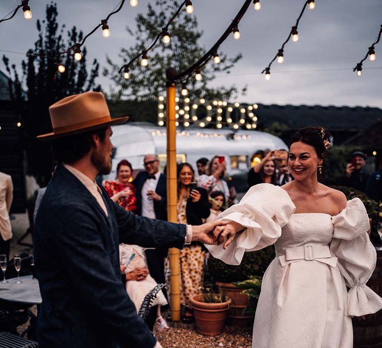 The bride and groom have their first dance together outdoors 